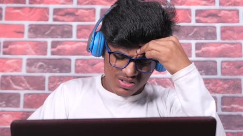 Young Adult Focused on Laptop with Headphones