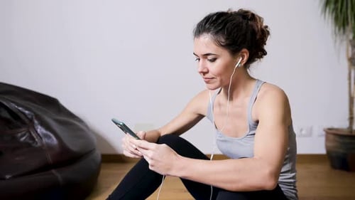 Young Woman Using Phone on Floor with Earphones