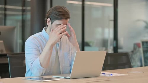 Man Frustrated While Working at Laptop in Office