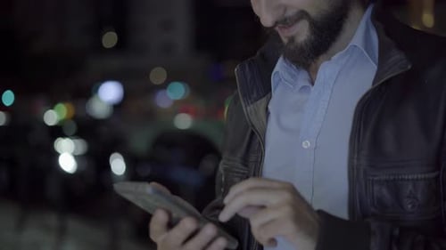 Man Uses Cellphone in the City at Night