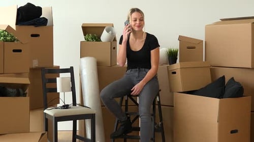 Woman Chatting on Phone Surrounded by Moving Boxes