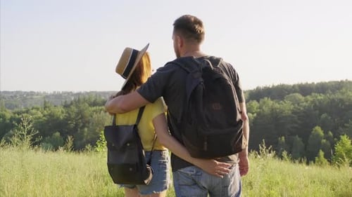 Happy Couple Enjoying Hike Together with Backpacks Hugging Back View