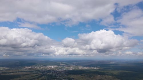 Aerial View From High Altitude of Distant City Covered with Puffy Cumulus Clouds Forming Before