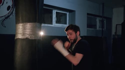 Alone Boxer Hits Punching Bag in Dark Gym in Slow Motion