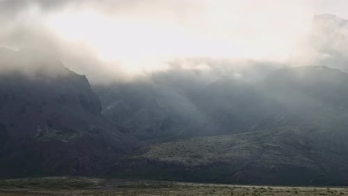 Sonnenbeschienene Wolken und Nebel bewegen sich über Berge