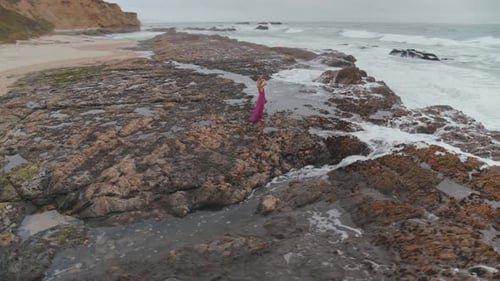 Woman Standing On The Rocky Shore