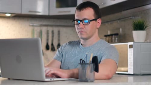Young Adult Typing on Laptop in Home Kitchen