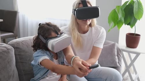 Mother and Child Wearing VR Headsets on Couch