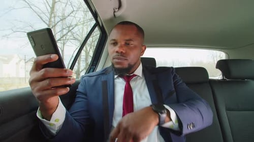 Young Adult Uses Smartphone in Car Backseat