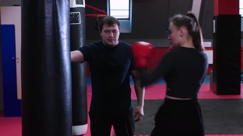 Woman Training Boxing Punches with Coach at Gym