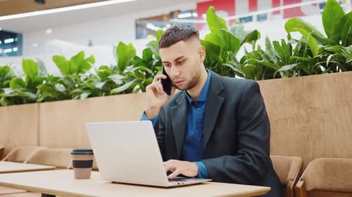 Businessman Working Online From Cafe and Talking on Phone