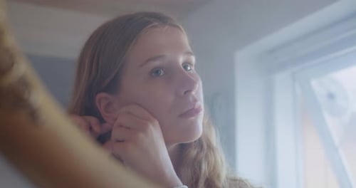 Young Woman Putting on Hoop Earrings at Home