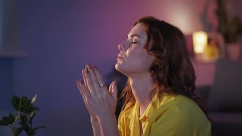 Woman Clasping Hands and Closing Eyes in Prayer