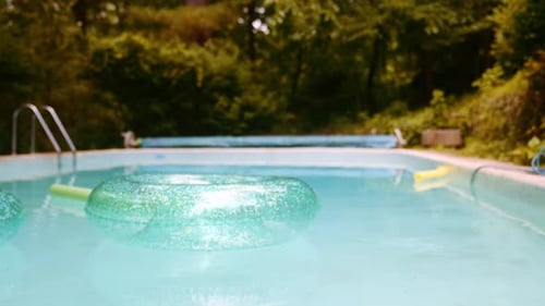 Glänzender aufblasbarer Kreis, der auf der Wasseroberfläche eines leeren Schwimmbades schwimmt