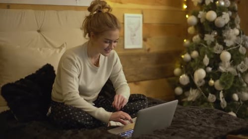 Woman Using Laptop on Bed at Christmas Time
