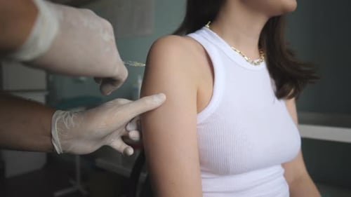 Nurse Giving Covid19 or Flu Antiviral Vaccine Shot to Female Patient at Health Clinic