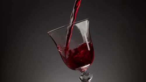 Pouring Red Wine Into Shiny Glass Over Black Background
