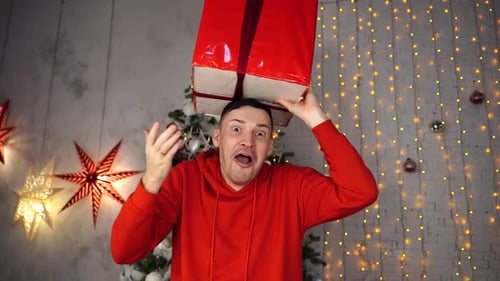 Man Holds Gift Overhead in Christmas Setting