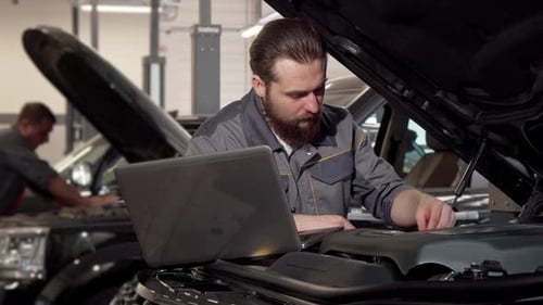 Car Service Worker Using Laptop, Examining Engine of a Car