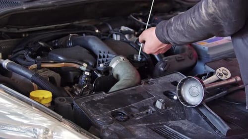 Kfz-Mechaniker überprüft den Motorölstand im Auto