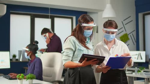 Coworkers with Face Visor in New Normal Office Comparing Graphs