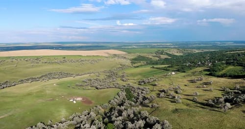 Panoramic View Of The Green Terrain Of The Hills With Lush Vegetation Under Cloudy Blue Sky. aerial