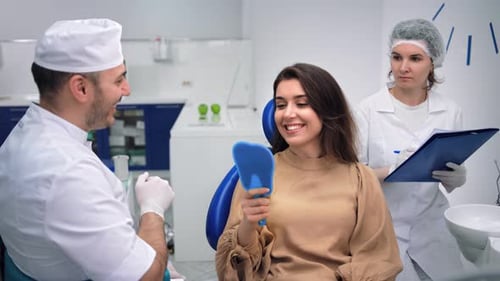 Patient Smiles at New Teeth in Dentist Mirror