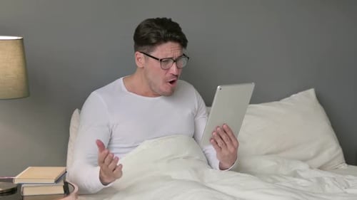 Man Sitting in Bed Talking Via Tablet Device