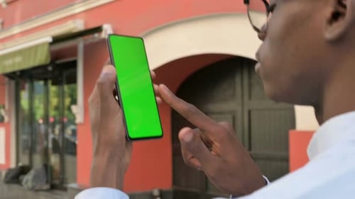 Rear View of African Man Looking at Smartphone with Green Chroma Screen