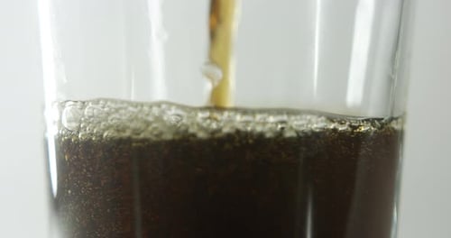 Brown Liquid Being Poured into Glass