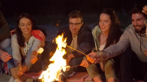 Friends Roasting Marshmallow on Camp Fire on Beach