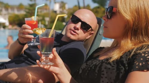 A Closeup of a Married Couple Relaxing in a Hotel Near the Pool They Lie on Sun Loungers and Drink