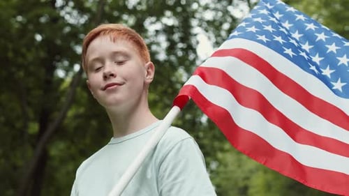 Young Boy Holding American Flag in Outdoor Setting