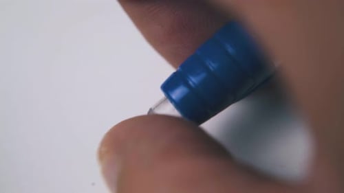 Man Clicks Automatic Pen in Plastic Case Above White Paper
