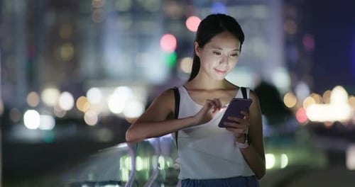 Woman use of mobile phone in city at night