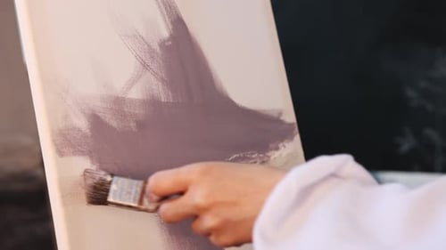 Art Studio Young Woman Artist Putting Purple Paint on a Canvas with a Brush