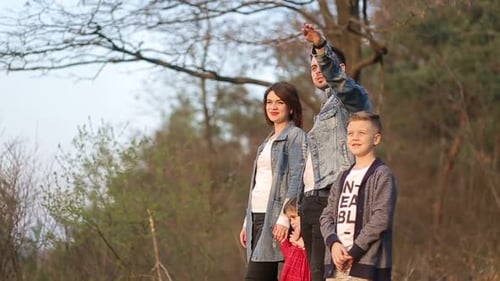 Happy family resting together on green grass in city park.