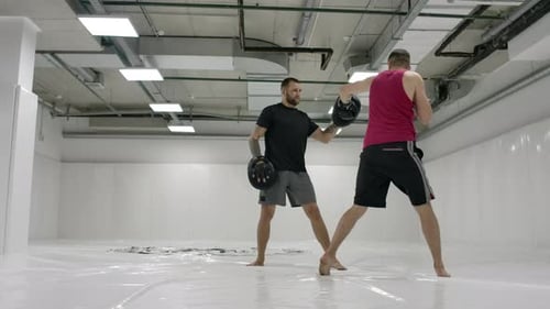 Boxing Trainer Works with Athlete in Gym
