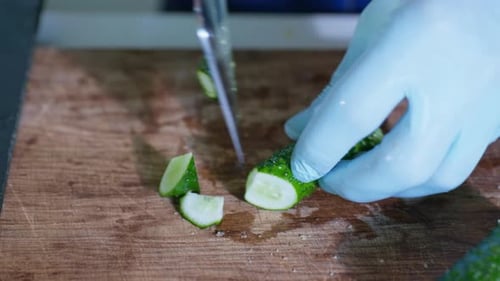 Cook with Gloves Slices of Fresh Healthy Cucumbers for Preparing Healthy Food or Salad on Cutting