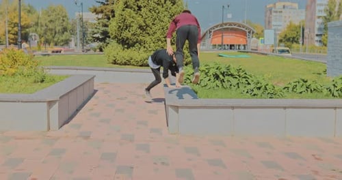 Two Guys Doing Stunts and Somersaults in the Park on the Curbs