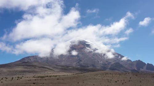 Vista aérea que muestra todo el volcán chimborazo desde detrás de una colina mientras vuela más cerca de él