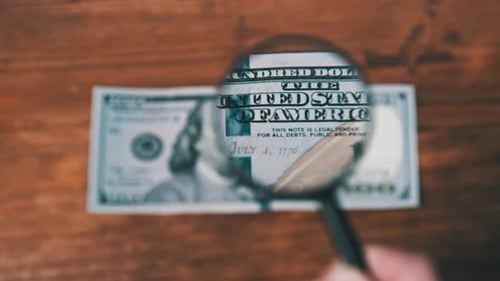 Examining One Hundred Dollar Bill with Magnifying Glass