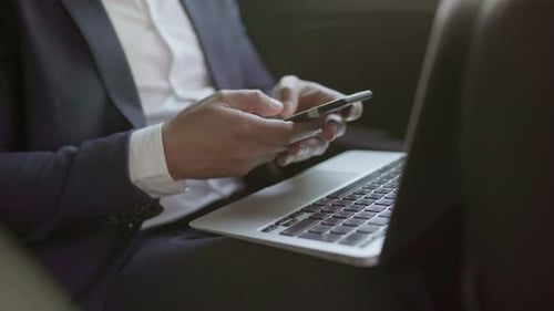 Mann benutzt Smartphone und Laptop im Auto
