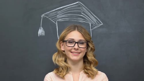 Smiling Graduate Poses in Front of Blackboard Drawing