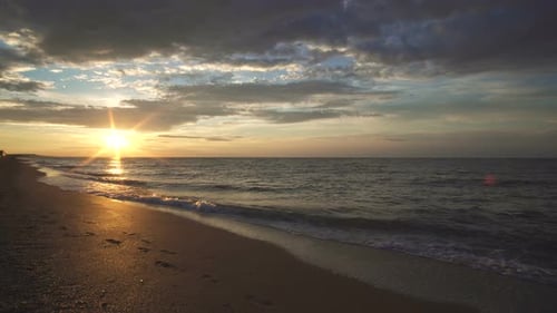 Sandy Beach At Sunset Washed By Water And Waves Of Sea