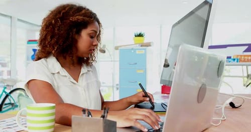Woman Works at Desk Using Computer and Tablet
