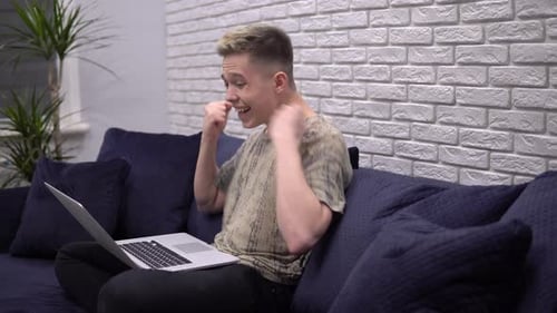 Young Adult Celebrating Success with Laptop Indoors