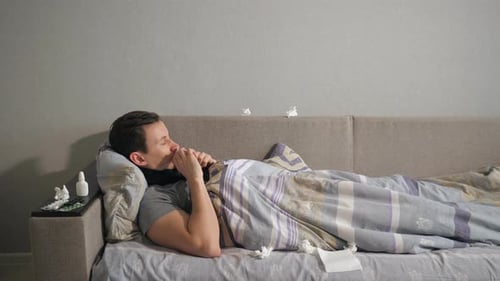 Der kranke Mann spritzt ein Medikament in die Nase, während er zu Hause auf der Couch liegt.