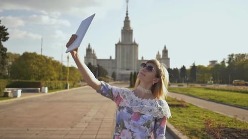 Woman takes photos on tablet in city setting