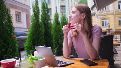 Young Woman Talking on the Phone in a Cafe on a Summer Terrace